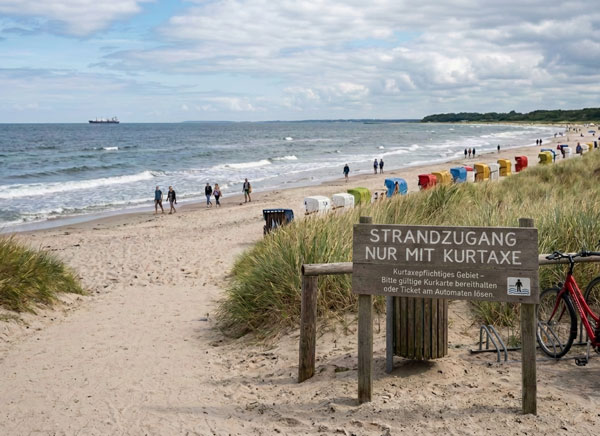behoerden-handling-digitale-kurtaxe-strandzugang Schild am Strandzugang mit der Aufschrift 'Strandzugang nur mit Kurtaxe' als Symbol für digitales Behörden-Handling im Hafen.